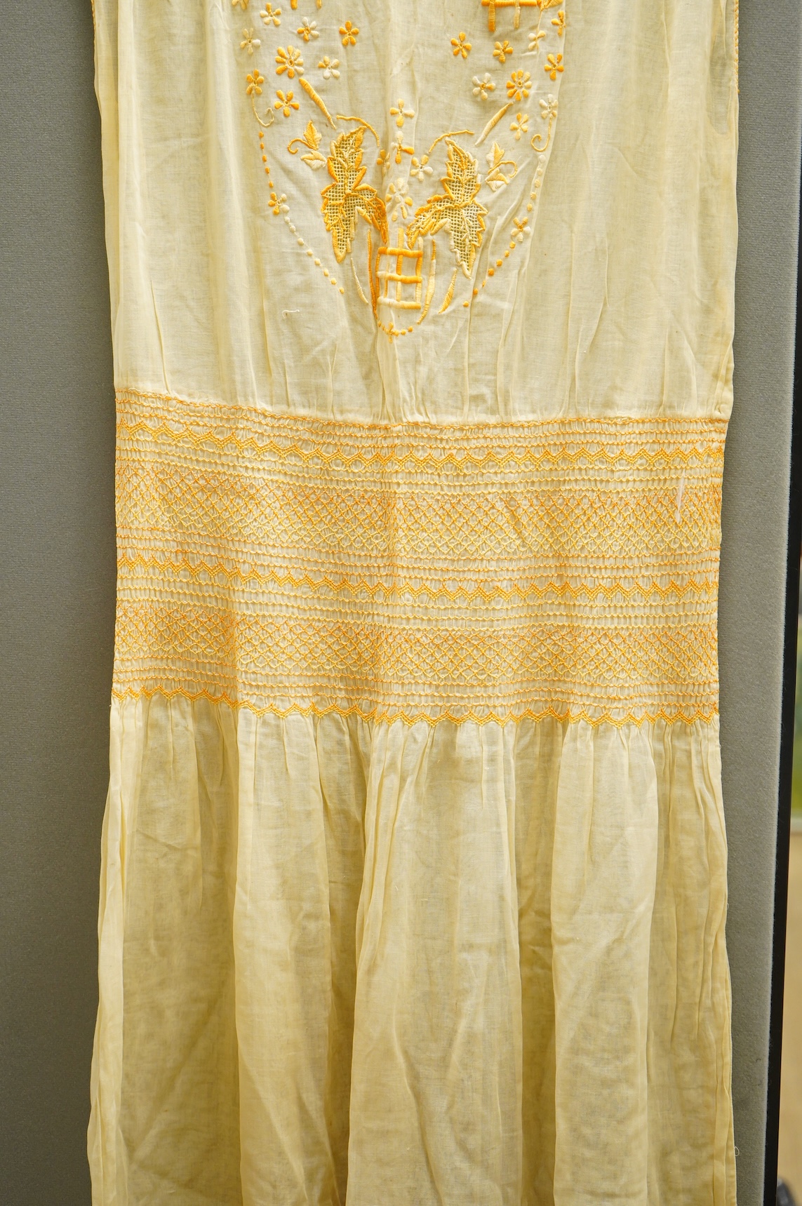 A 1920-30's fine yellow cotton gauze, embroidered and smocked day dress. 117cm long. Condition - good